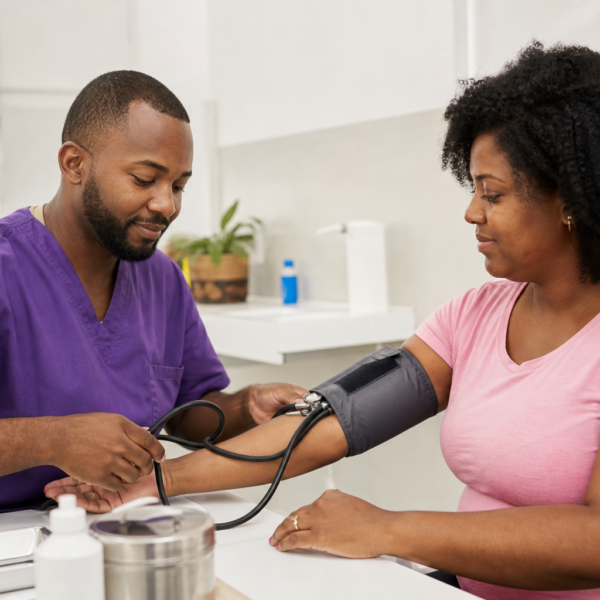 Mulher negra aferindo a pressão arterial em consulta preventiva
